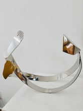 Load image into Gallery viewer, A sculpture with fluidity, SOSSEGO, which can be viewed from every perspective, even if it has a "main" side that defines positioning. Luiz Campoy takes us on a marvelous adventure with his sense of humor and his deft expertise in creating this three-dimensional, stainless steel sculpture.  Artist: Luiz Campoy  Material: Stainless Steel  Dimensions: 60 x 30 x 50cm  Genre: Sculpture  Worldwide Shipping